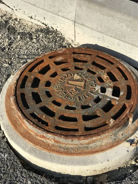 Rusty iron manhole set into asphalt road surfaces — Stock Photo, Image