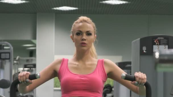 Hermosa chica rubia ocupada en el gimnasio en el interior — Vídeos de Stock