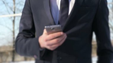 Gümüş akıllı telefon sokakta kışın tutan adam