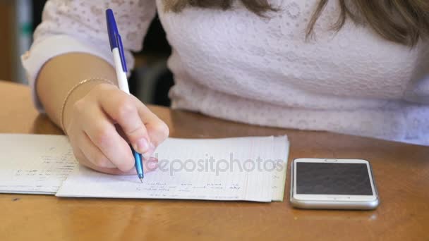 Школьница пишет текст в тетрадке. Крупный план — стоковое видео