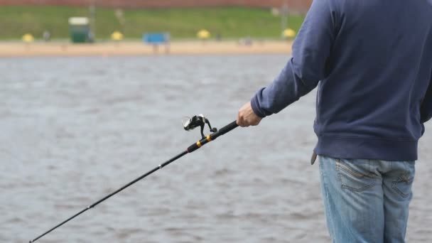 El hombre está pescando con una caña en el fondo del río — Vídeo de stock