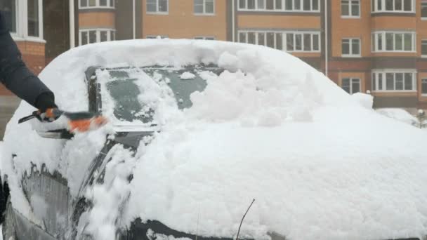 Чоловік прибирає машину зі снігу — стокове відео