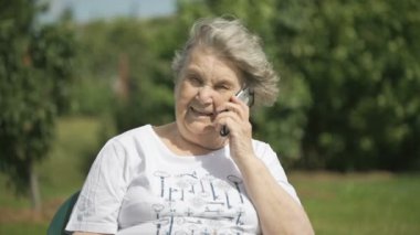 Gülümseyen yaşlı kadın bir akıllı telefon kullanarak söz