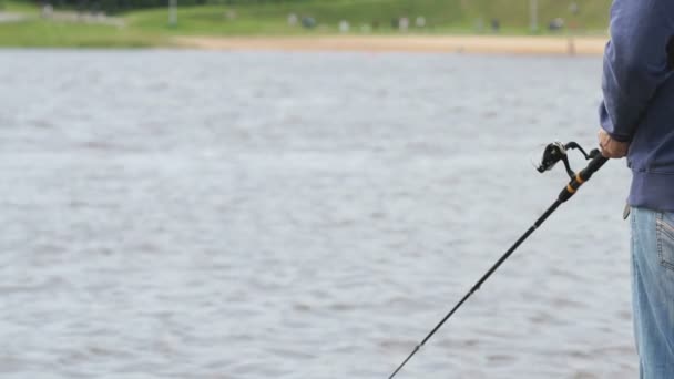 El hombre está pescando con una caña en el fondo del río — Vídeo de stock