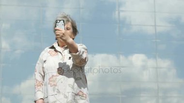 Olgun yaşlı kadın bir akıllı telefon kullanarak fotoğraf çeker