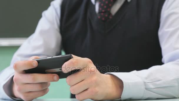 Colegial desconocido sosteniendo teléfono inteligente negro — Vídeo de stock