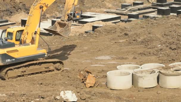 Yellow excavator on a construction site in summer — Stock Video