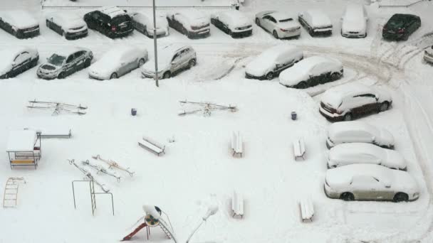 Автомобілі та дитячий майданчик під снігом — стокове відео