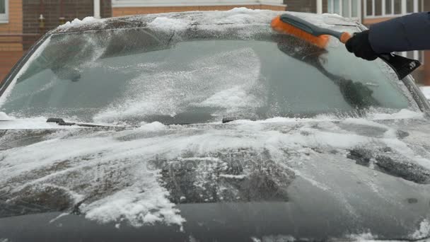 Мужчина убирает машину от снега — стоковое видео