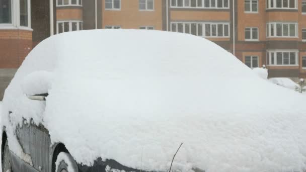 Неизвестный автомобиль, покрытый снегом во дворе — стоковое видео