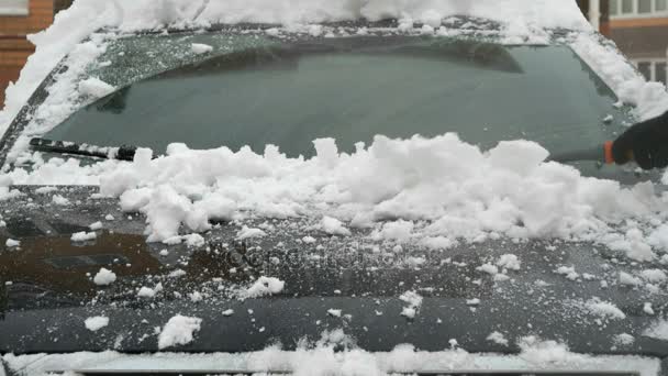 Чоловік прибирає машину зі снігу — стокове відео