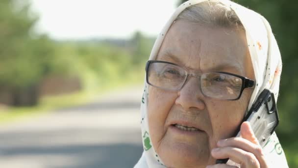 Rijpe oude vrouw gesprekken buitenshuis gebruik van smartphone — Stockvideo