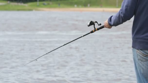 El hombre está pescando con una caña en el fondo del río — Vídeo de stock
