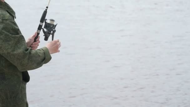 Неизвестный рыбачит на фоне реки — стоковое видео