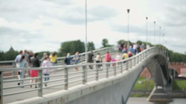 Mensen lopen op de voetgangersbrug over de rivier — Stockvideo