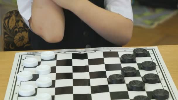 Het kind speelt dammen in de kleuterschool binnenshuis — Stockvideo