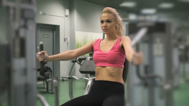 Hermosa chica rubia ocupada en el gimnasio en el interior — Vídeos de Stock