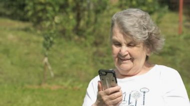 Yaşlı kadın görüşmeler bir akıllı telefon kullanarak gülümseyen