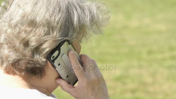 Idős asszony beszél, használ egy okos telefon, szabadban — Stock videók