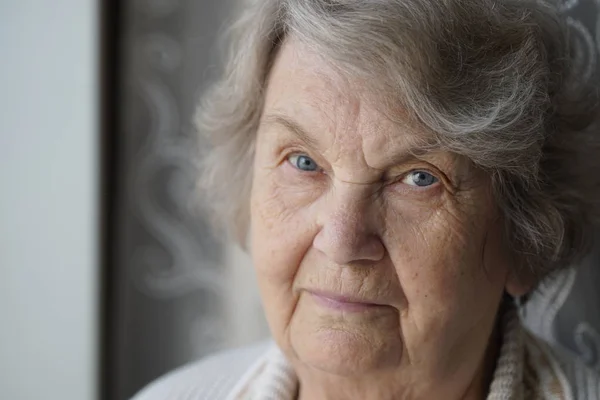 Porträt einer alten Frau im Alter von 80 Jahren in Innenräumen Stockbild