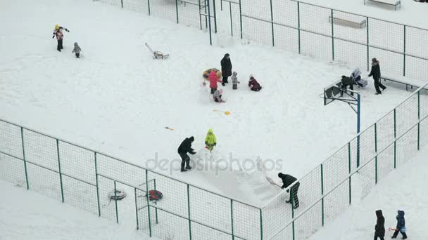 Mensen spelen op omheinde binnenplaats in de winter — Stockvideo