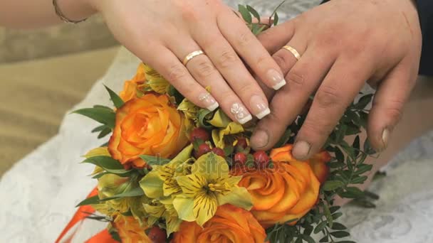 Close-up of hands of bride with bouquet and groom — Stock Video