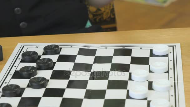 The child plays checkers in kindergarten indoors — Stock Video