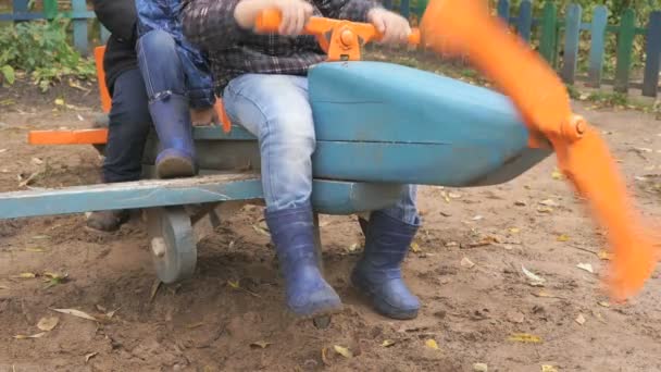 Дети сидят на игрушечном синем самолете — стоковое видео