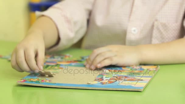 Bambino sconosciuto che raccoglie puzzle a tavola — Video Stock