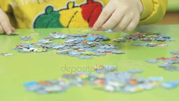 Unknown child collecting puzzles at the table — Stock Video
