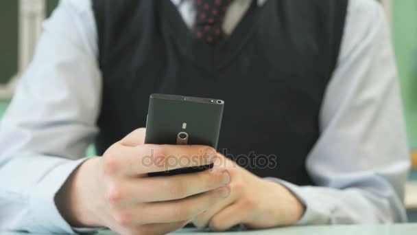 Colegial desconocido sosteniendo teléfono inteligente negro — Vídeos de Stock