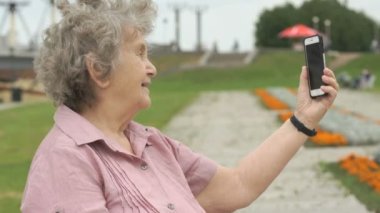Olgun yaşlı kadın bir akıllı telefon kullanarak fotoğraf çeker