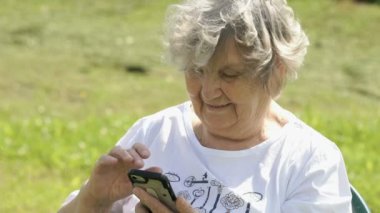 Olgun yaşlı kadın bir smartphone açık havada tutar