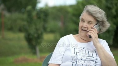 Yaşlı kadın bir akıllı telefon açık havada kullanarak söz