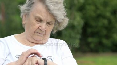 Yaşlı kadın bileklik fitness izleme cihazı görünüyor