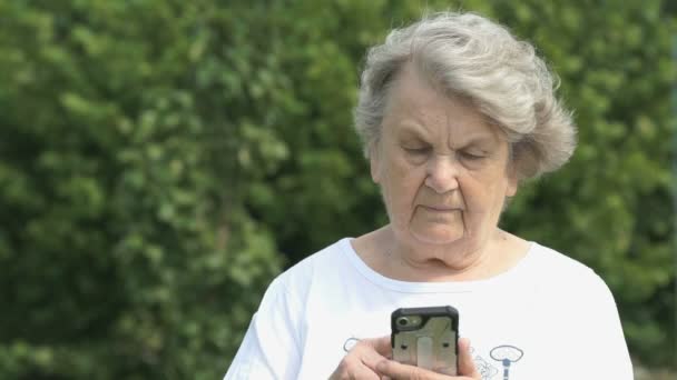 Rijpe oudere vrouw houdt een slimme telefoon buitenshuis — Stockvideo