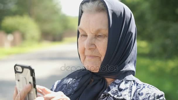 Улыбающаяся взрослая женщина показывает смартфон на улице — стоковое видео