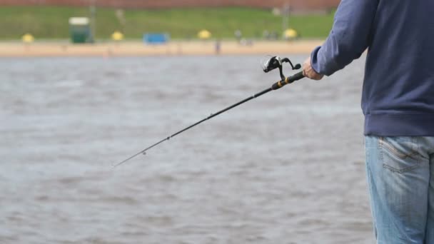 Mannen är fiske med ett spö på bakgrund av floden — Stockvideo