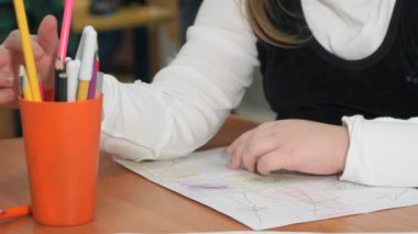 Küçük kız renkli kalemler kullanarak resim çizer