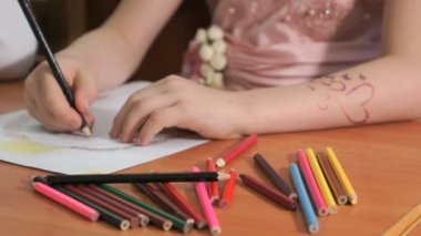 Çocuk renkli kalemler kullanarak resim çizer