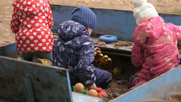 Маленькі діти грають з піском у пісочниці — стокове відео