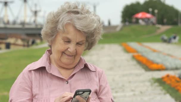 Улыбающаяся пожилая женщина держит смартфон — стоковое видео