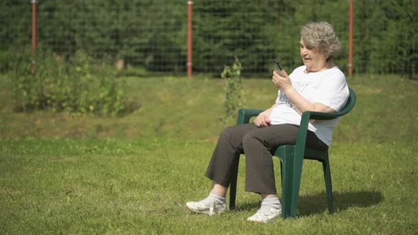 Vieja hablando usando un teléfono móvil al aire libre — Vídeos de Stock