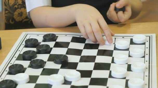 Het kind speelt dammen in de kleuterschool binnenshuis — Stockvideo