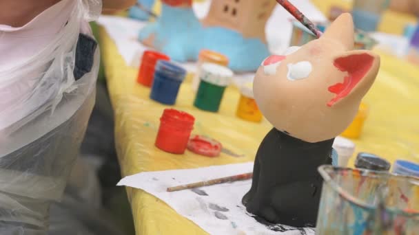 Brosses à peindre pour enfants sur la figure en argile à l'extérieur — Video