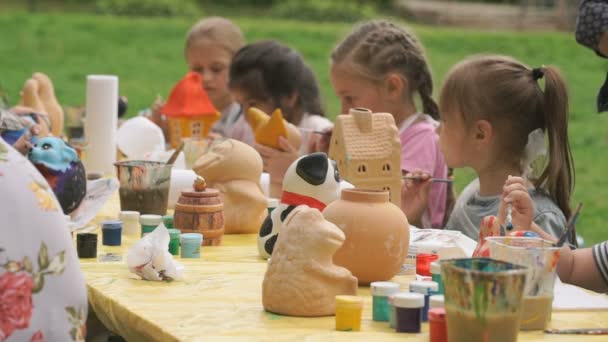 Dzieci malowania pędzle na gliny figury na zewnątrz — Wideo stockowe