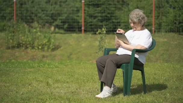 La donna anziana tiene un tablet per computer all'aperto — Video Stock