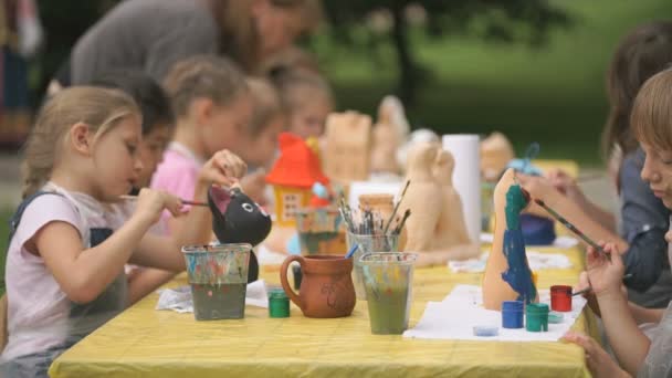 Děti Malování kartáče na hliněné postavy venku — Stock video