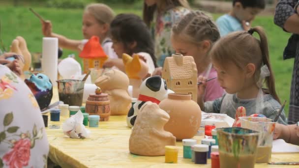 Crianças pincéis de pintura em figuras de argila ao ar livre — Vídeo de Stock