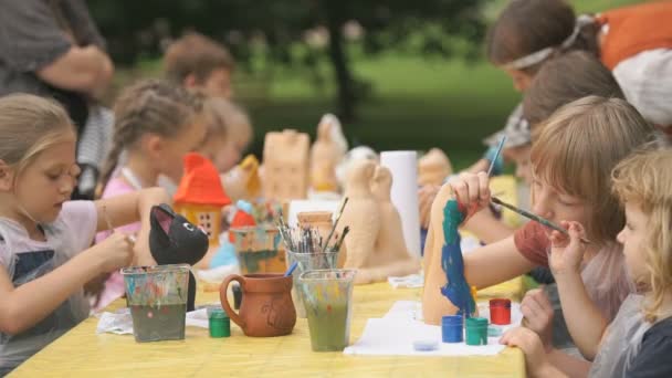 Barn målar borstar på lera figurer utomhus — Stockvideo